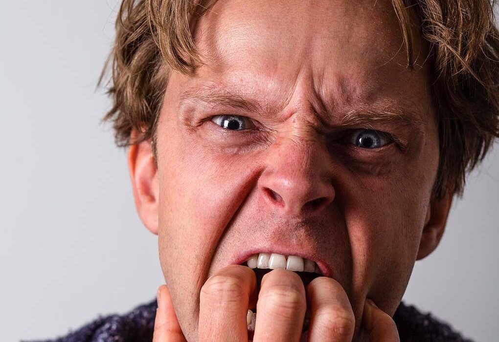 homem loiro roendo as unhas de nervosismo